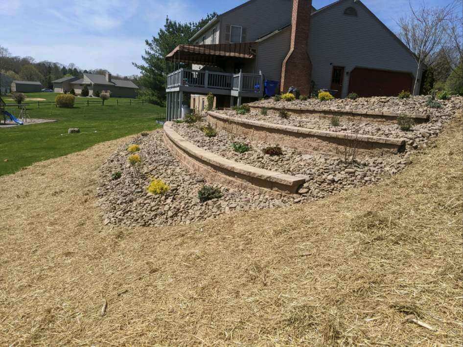 retaining walls in a hillside with new bushes and stone in each level