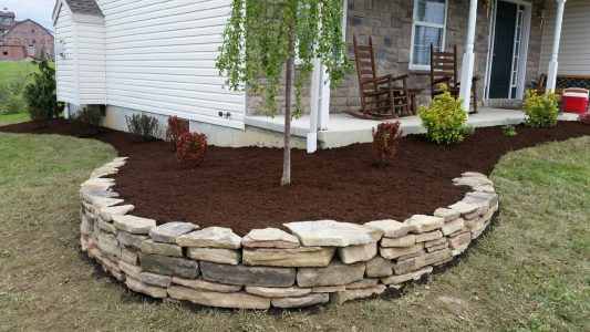 Natural stone retaining wall with landscaping Natural stone retaining wall with landscaping