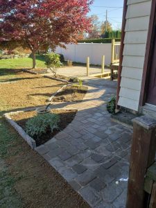 stone pathway wrapping around a house with flowerbeds incorporated at corners and edges