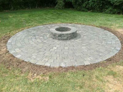 stone firepit and circular patio around it with nearly uniform stone bricks