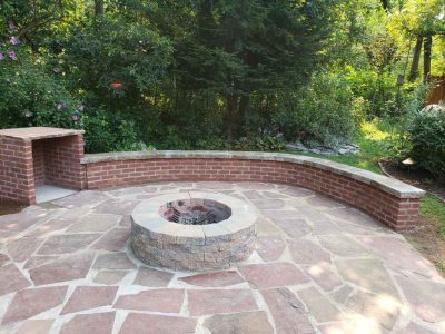 brick firepit and storage area with a brick wall and walkway around the red stone and sand ground