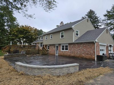 freshly finished stone patio behind a brick house with short walls bordering the corners freshly finished stone patio behind a brick house with short walls bordering the corners