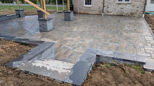 Finished paver patio steps leading into a custom pergola and outdoor living space